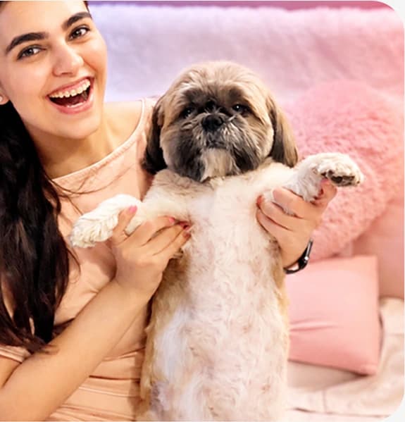 A creator laughing with her dog on a pink sofa